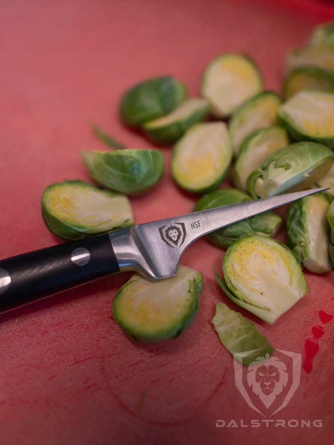 Dalstrong gladiator series 3 piece paring knife with black handles and slices of brussel sprouts.