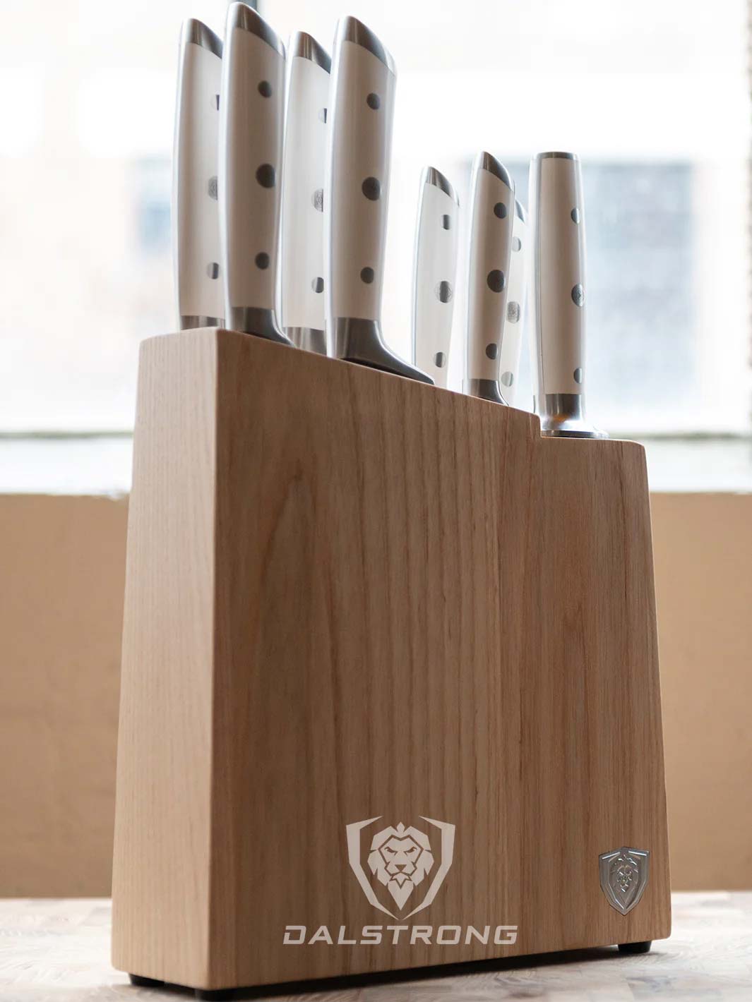 Dalstrong gladiator series 8 piece knife set with white handles inside it's block on a table.