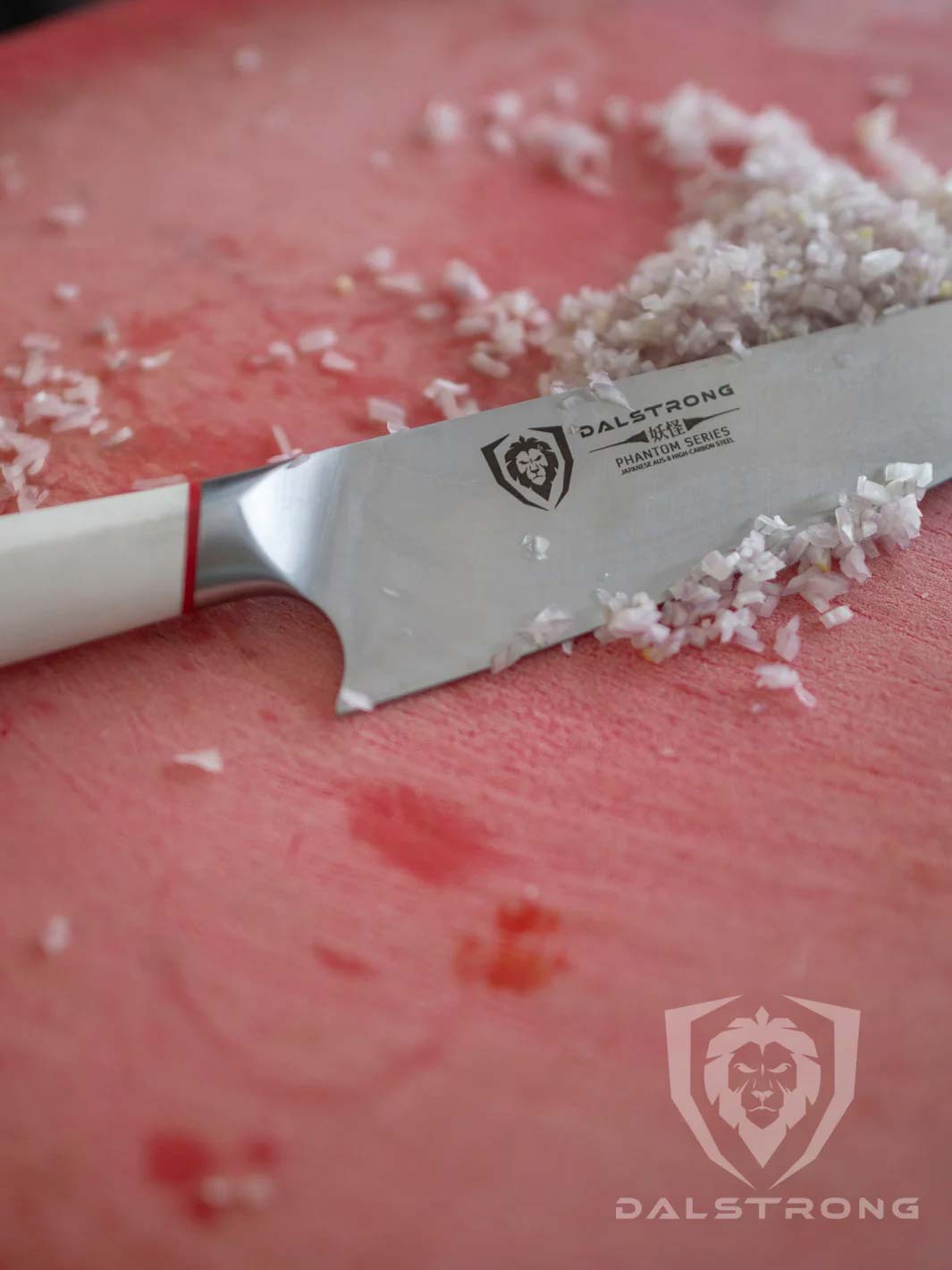 Dalstrong phantom series 8 inch chef knife with white handle and minced onions on a red cutting board.