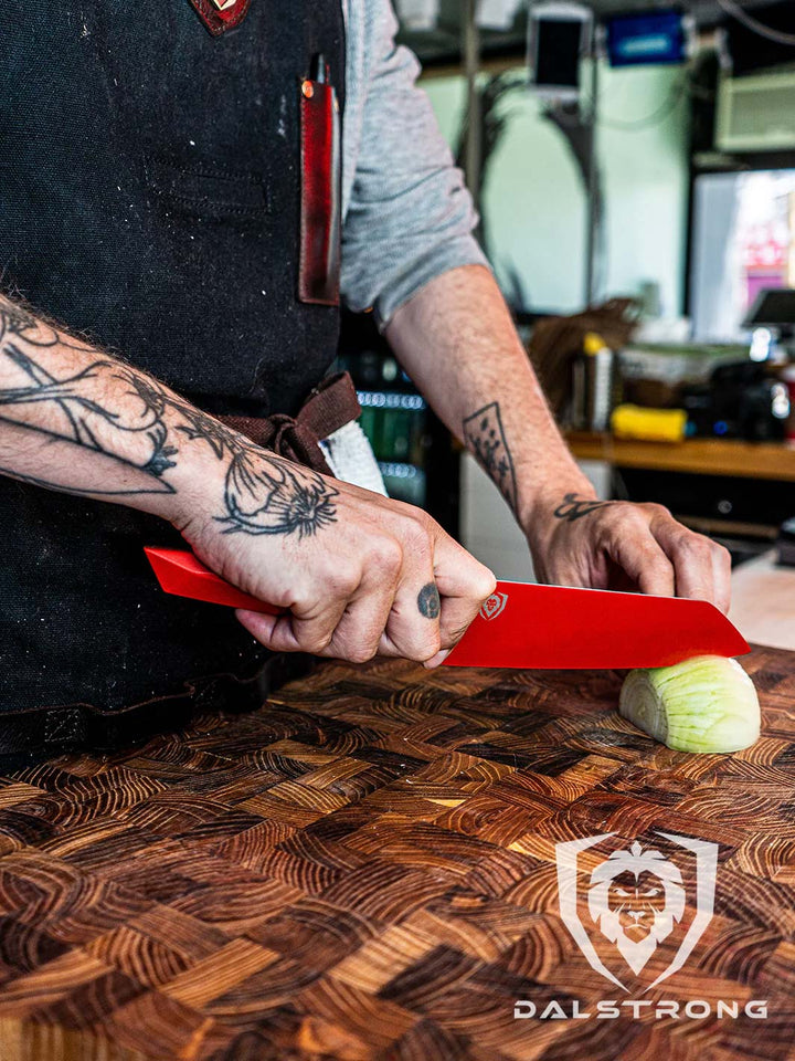 Dalstrong shadow series 7 inch santoku knife red edition with a sliced onion on a cutting board.