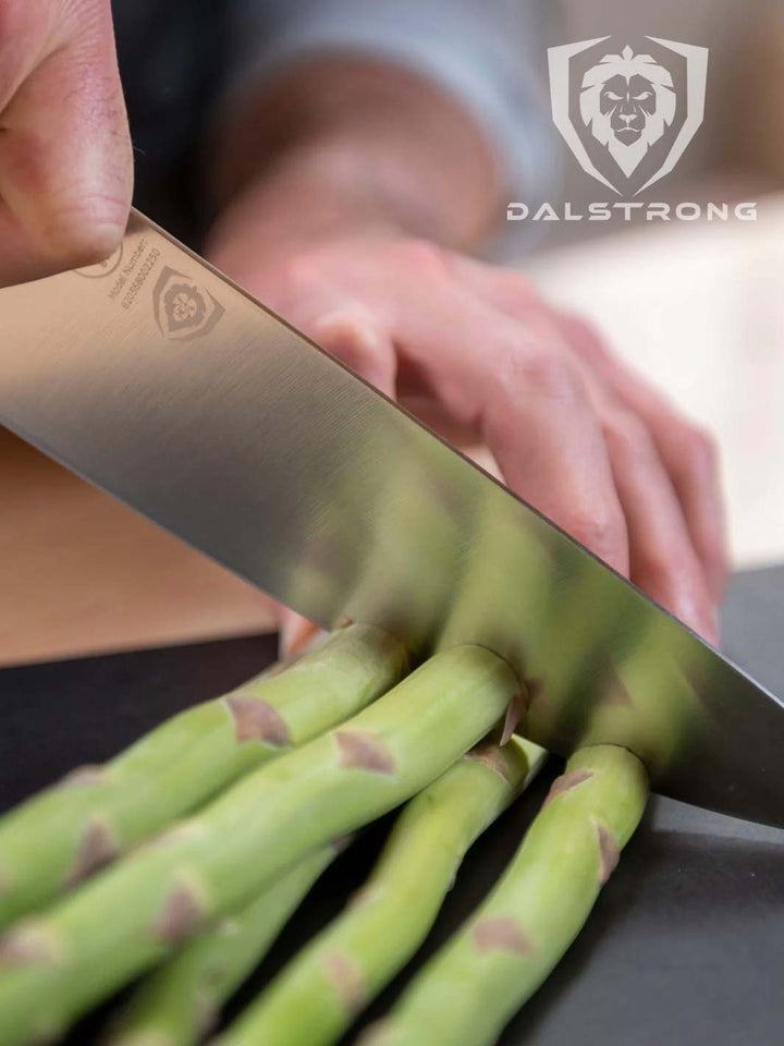 Dalstrong vanquish series 8 inch chef knife with black handle slicing asparagus.