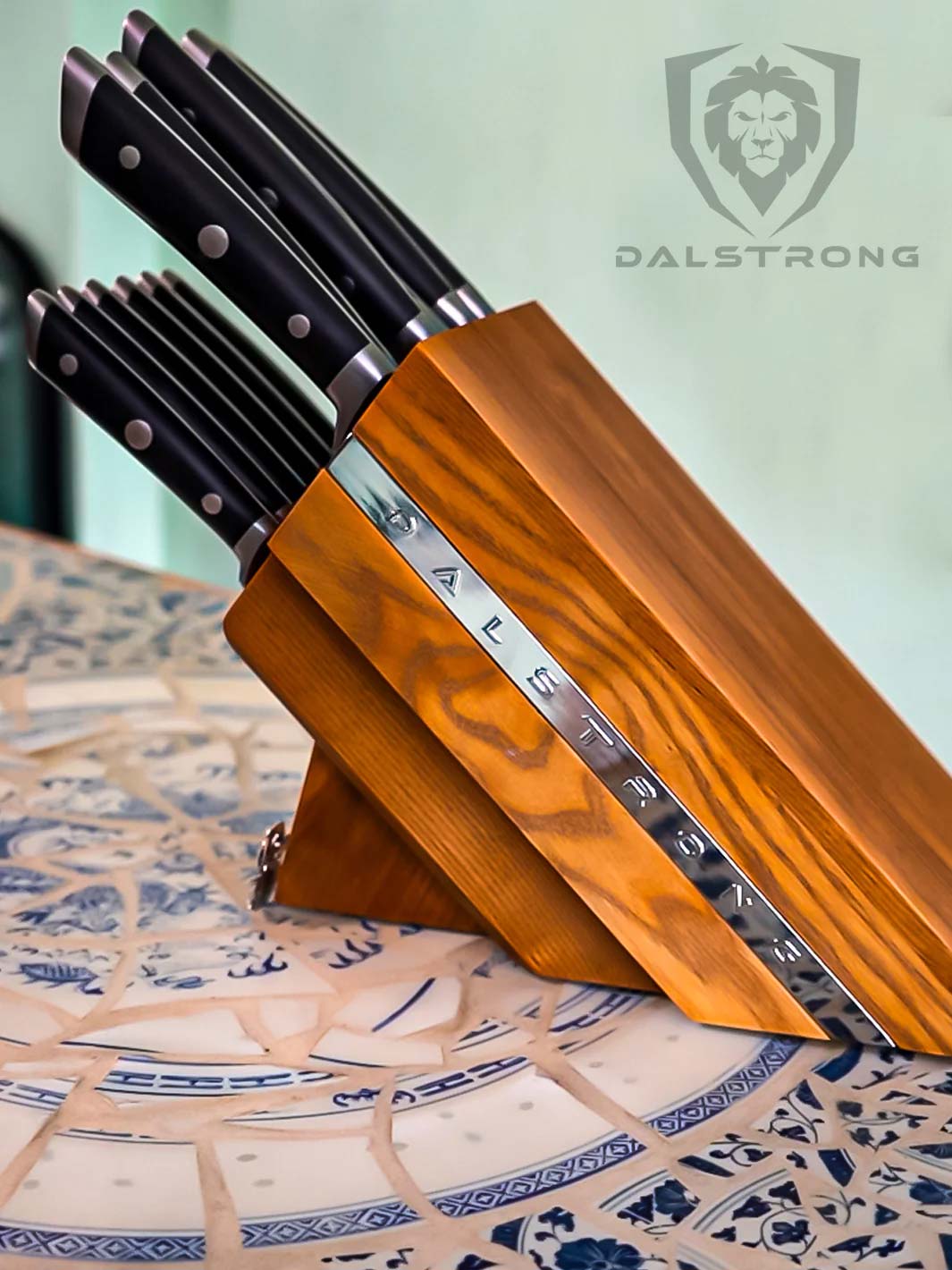 Dalstrong gladiator series 12 piece knife block set with black handles on top of a table.