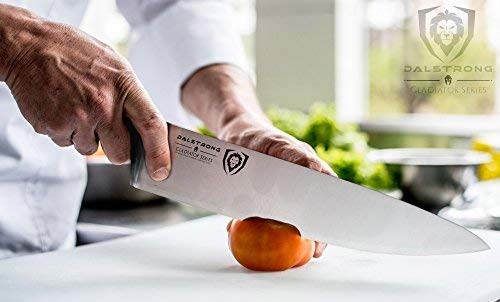 Man's hand holding the dalstrong gladiator series 10 inch chef knife with black handle with a fruit.