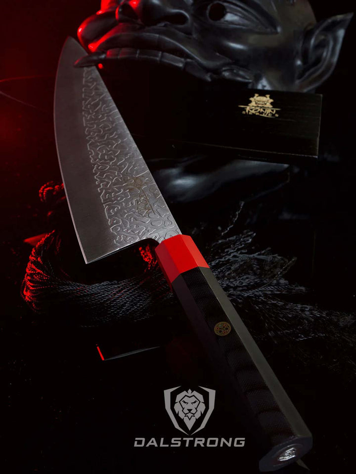 Dalstrong roning series 8 inch chef knife with black handle and sheath beside a oni mask.