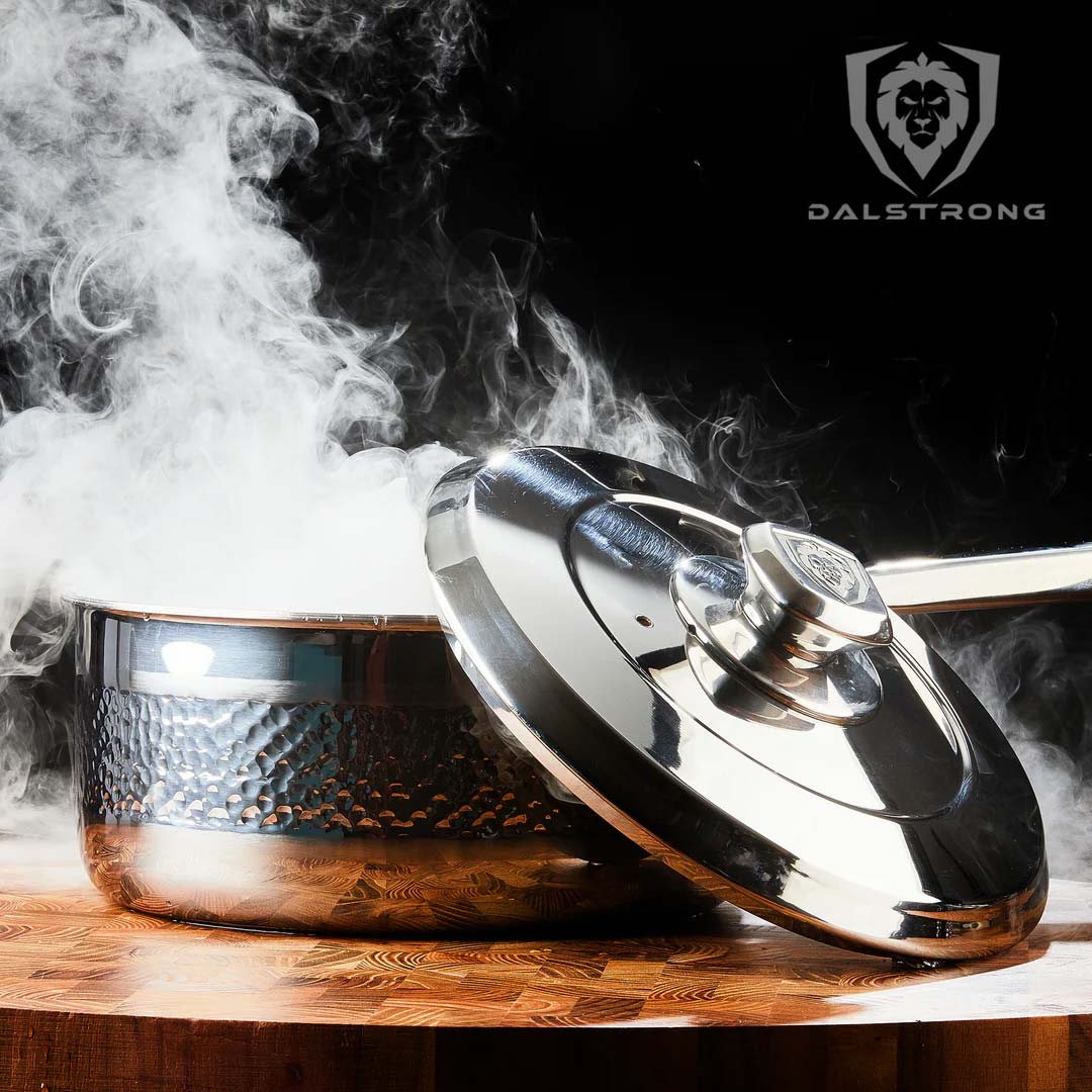 Dalstrong avalon series 3 quart stock pot hammered finish silver with steam coming out of it on a cutting board.
