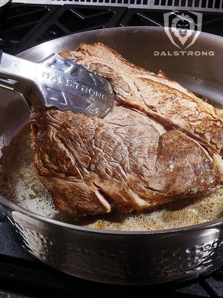 Dalstrong avalon series 12 inch saute frying pan hammered finish silver with a huge steak inside.