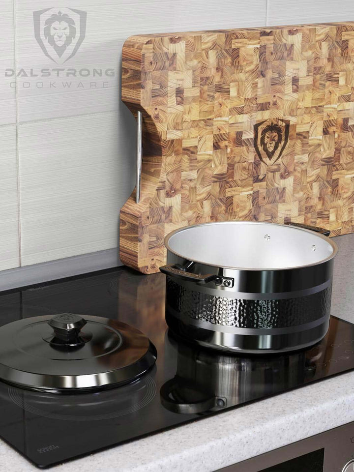 Dalstrong avalon series 8 quart stock pot hammered finish black with a dalstrong cutting board at the side.