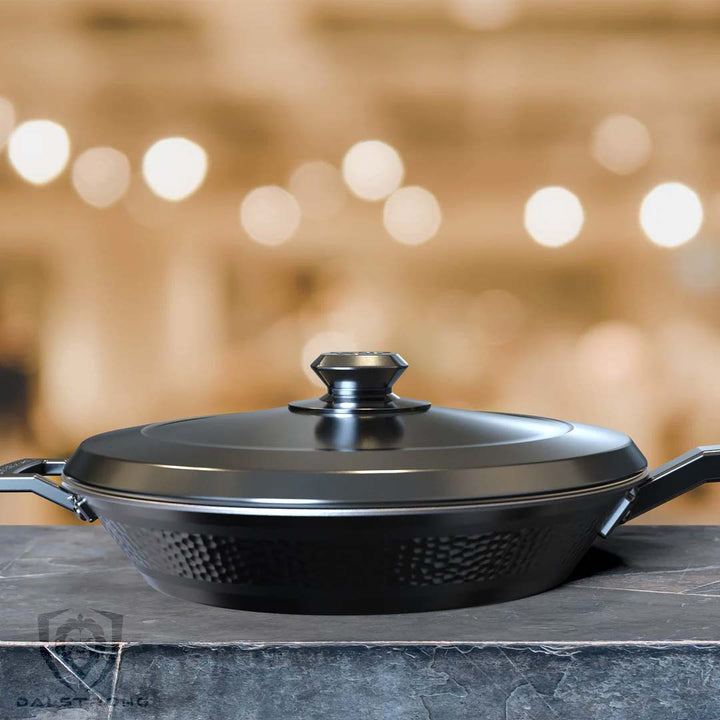 Dalstrong avalon series 12 inch frying pan and skillet hammered finish black with black lid on a marble table.