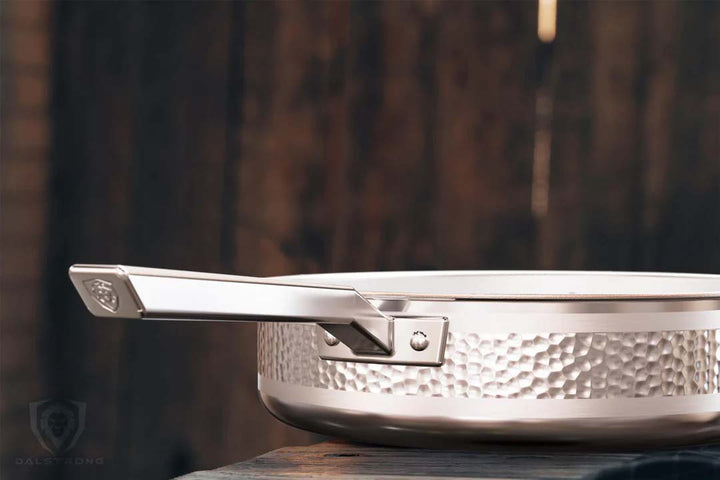 Dalstrong avalon series 12 inch saute frying pan hammered finish silver on a wooden table.