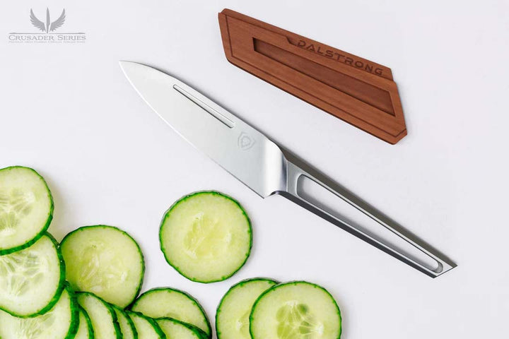 Dalstrong crusader series 3.5 inch paring knife with german steel handle beside slices of cucumber.