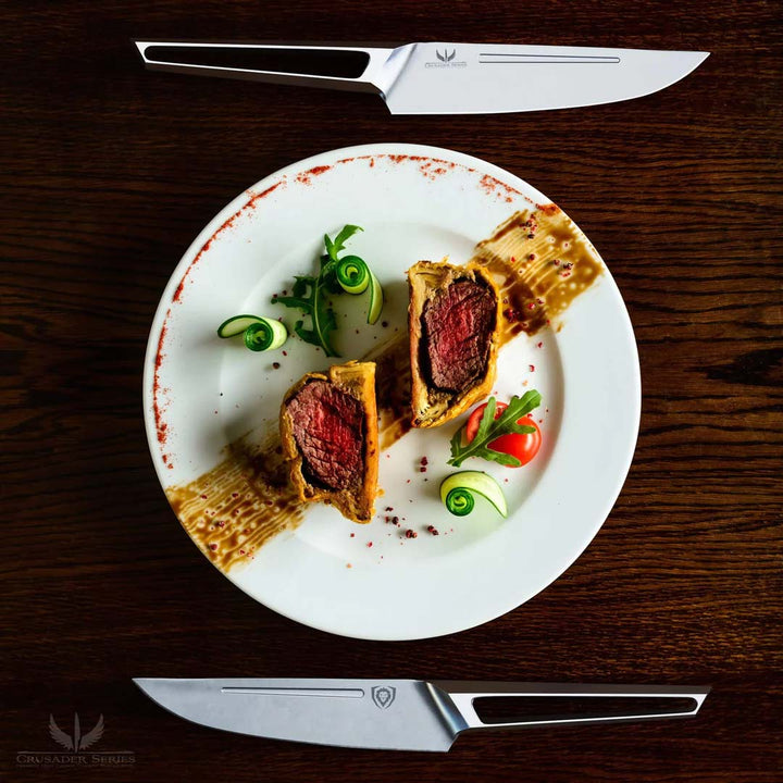 Dalstrong crusader series 5 piece steak knife set with slices of beef wellington on a plate.