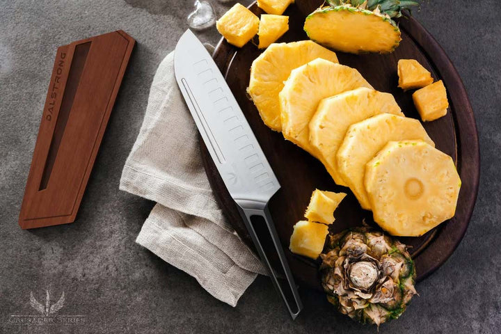 Dalstrong crusader series 7 inch santoku knife with german steel handle with slices of pineapple on a board.
