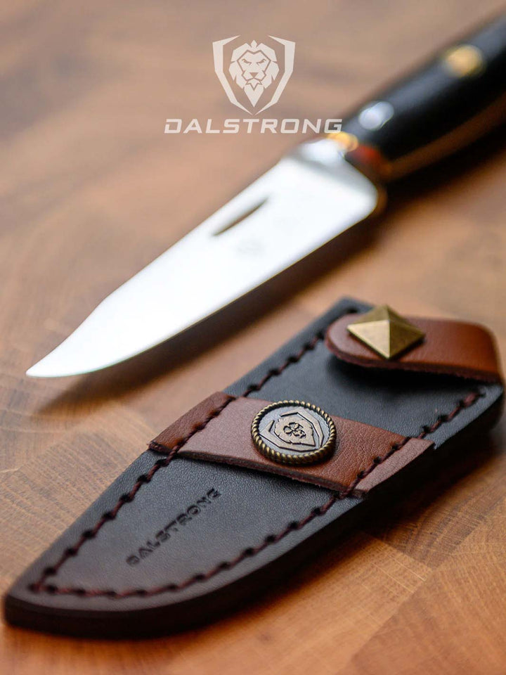 Dalstrong centurion series 3.5 inch paring knife beside it's sheath on a cutting board.