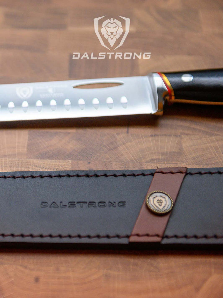 Dalstrong centurion series 12 inch slicing and carving knife with black handle beside it's black sheath.