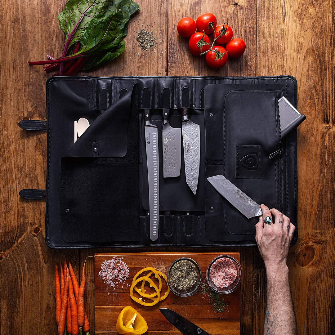 Dalstrong full grain leather midnight black vagabond knife roll with knives inside and surrounded by vegetables.