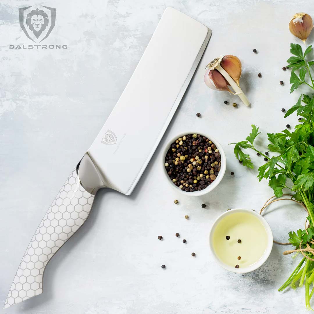 Dalstrong frost fire series 6.5 inch nakiri knife with white handle and green herbs.