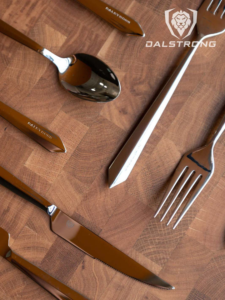 Dalstrong 20 piece flatware cutlery set silver stainless steel service for 4 on top of a board.