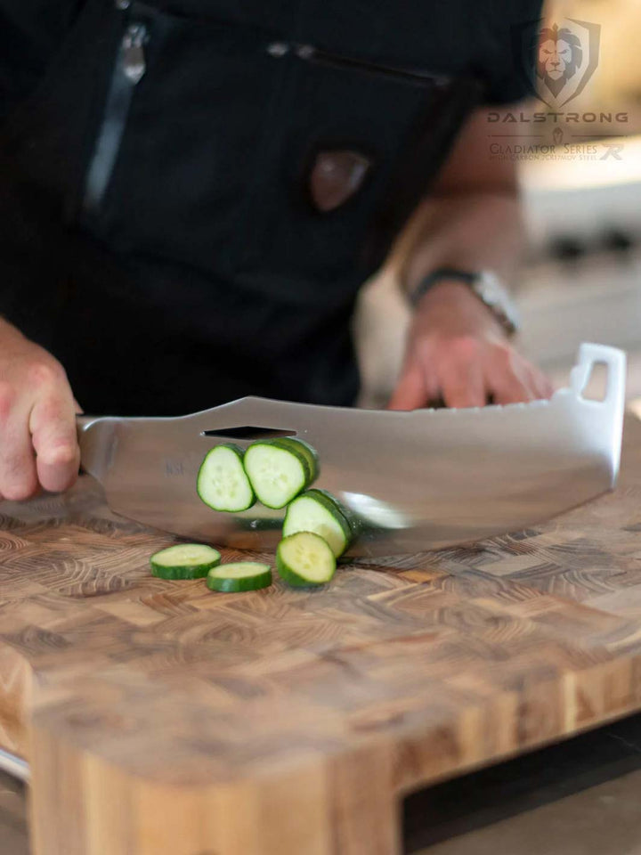 Dalstrong gladiator series 12 inch rocking cleaver knife slicing cucumber on a cutting board.