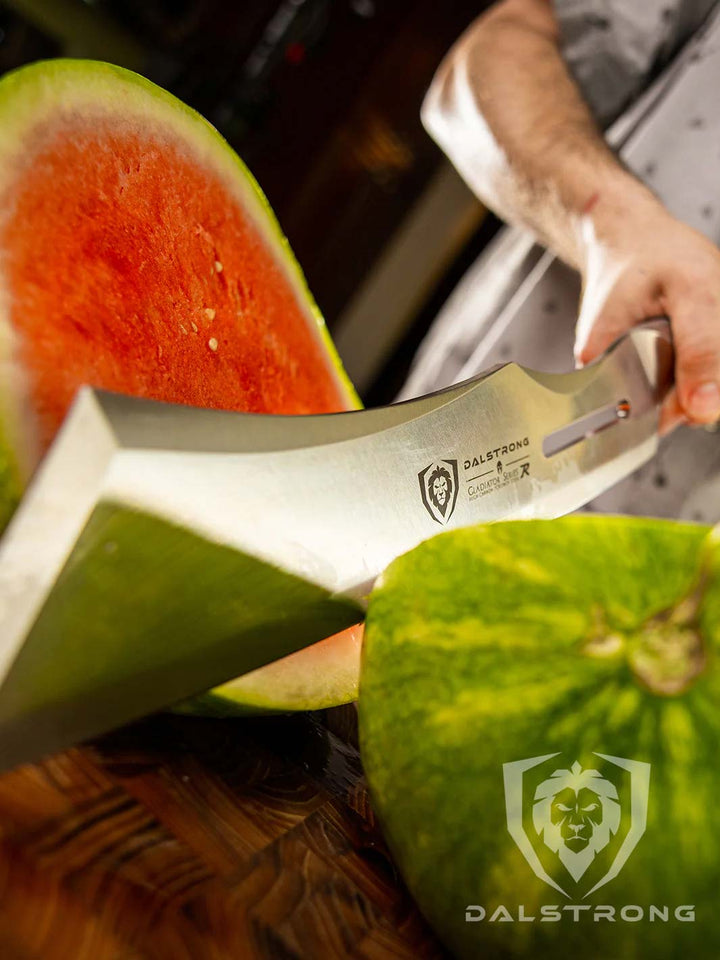 Man slicing a melon in half with the dalstrong gladiator series 14 inch annihilator cleaver knife on a wooden board.