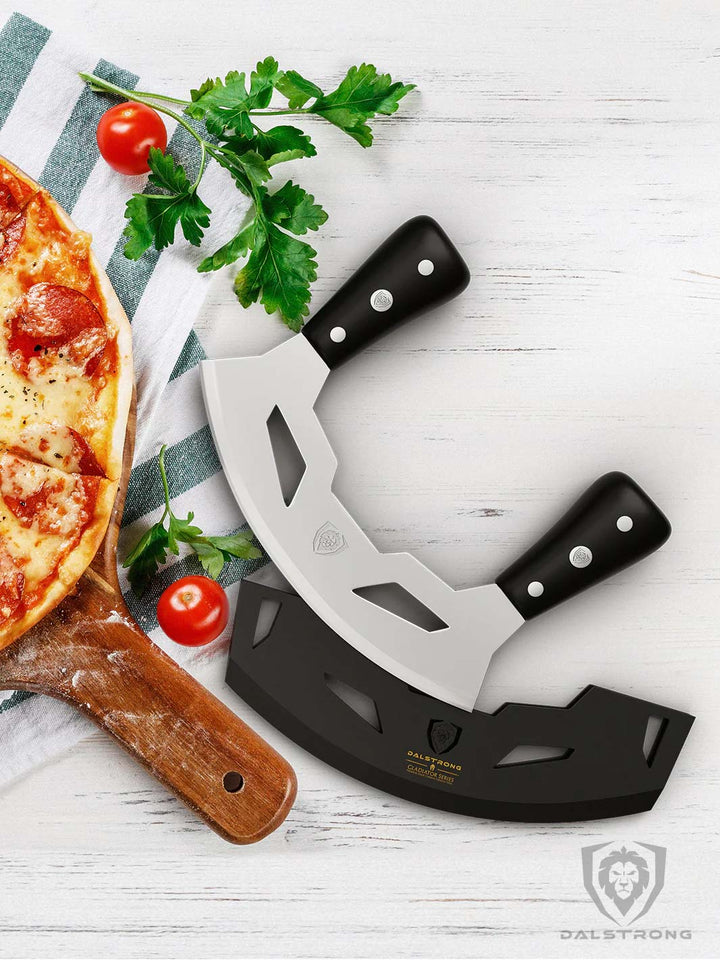 Dalstrong gladiator series 8.5 inch mezzaluna knife with black handle and sheath beside a pizza.