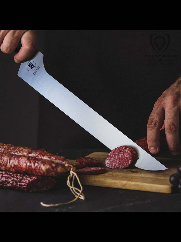 Dalstrong gladiator series 12 inch offset slicer knife with black handle and sheath beside a sliced sausage.