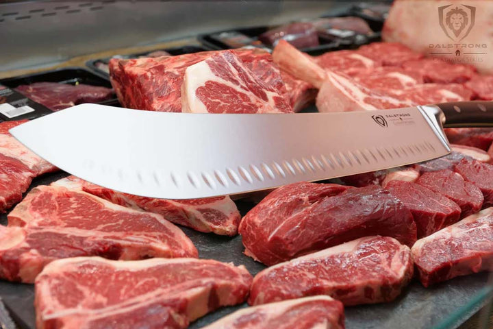 Dalstrong gladiator series 14 inch bull nose butcher knife with black handle on top of different cuts of steaks.
