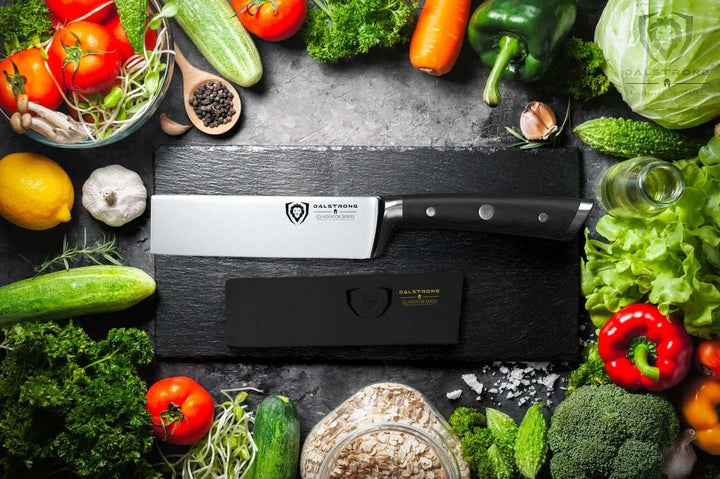 Dalstrong gladiator series 6 inch produce knife with black handle and sheath surrounded of different kinds of vegetables.