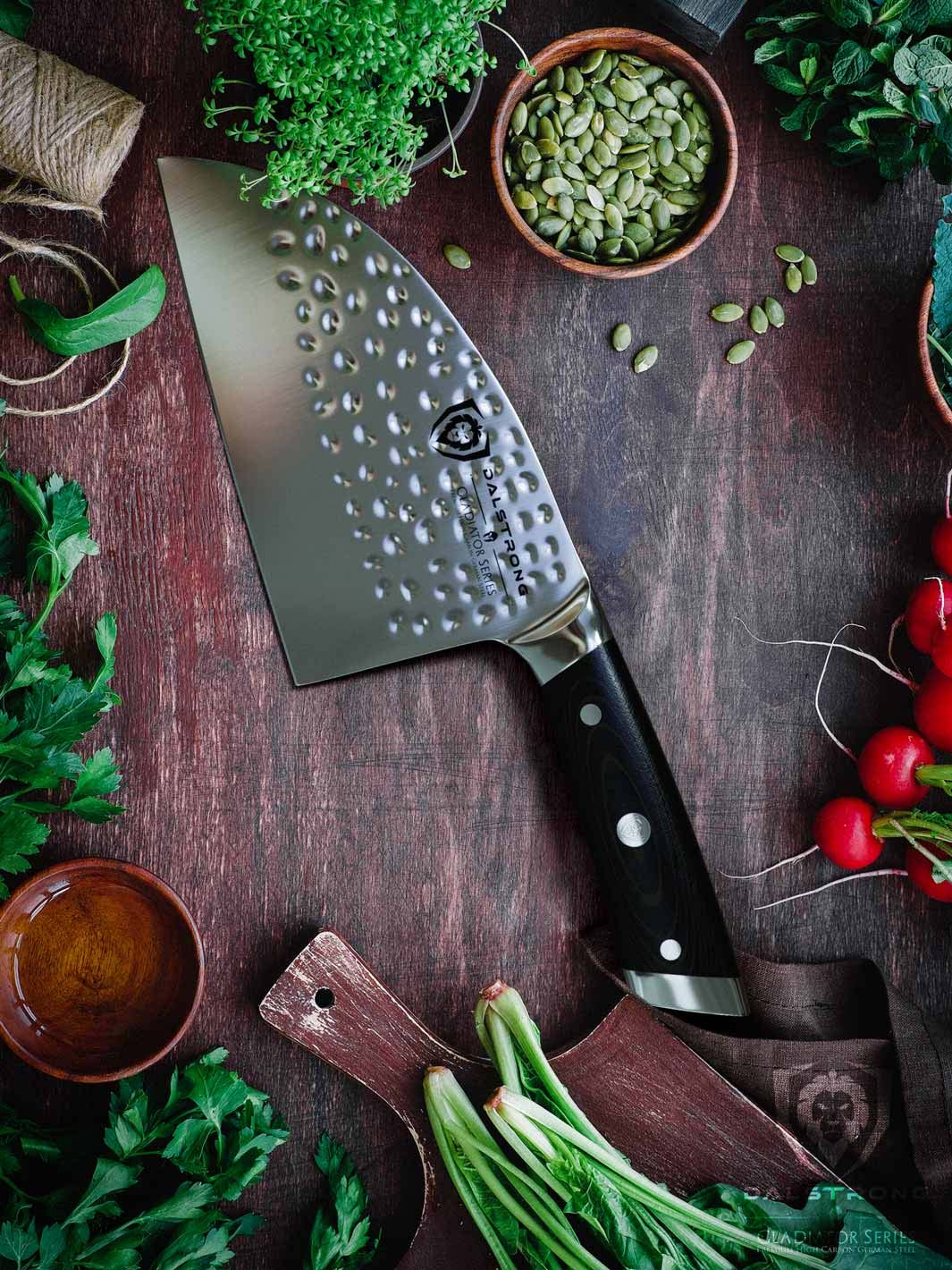 Dalstrong gladiator series 7.5 inch serbian knife with black handle surrounded by different kinds of green herbs.