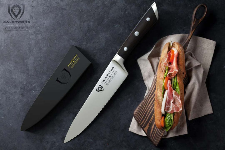 Dalstrong gladiator series 7.5 inch serrated chef knife with black handle and sheath beside a sandwich.