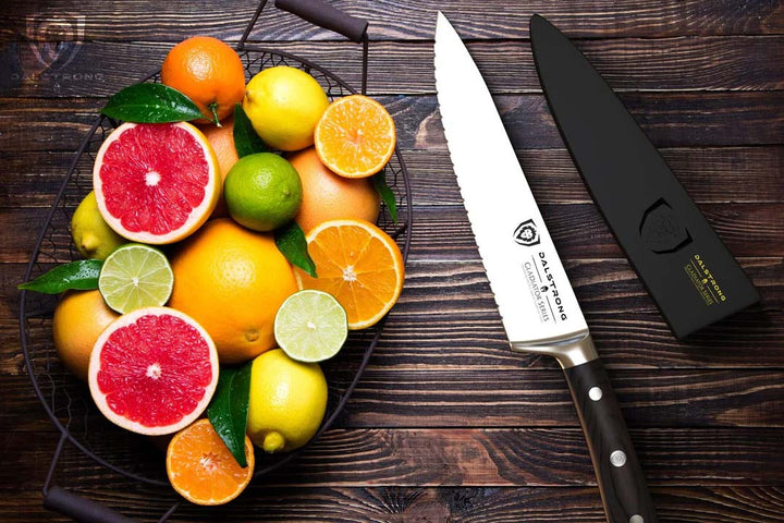 Dalstrong gladiator series 7.5 inch serrated chef knife with black handle and sheath beside a basket full of fruits.