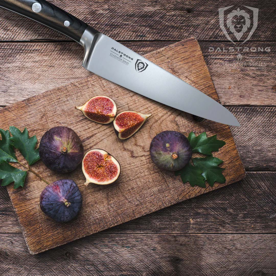 Dalstrong gladiator series 7 inch chef knife with black handle and slices of fig on a wooden cutting board.