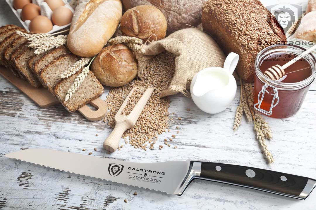 Dalstrong gladiator series 8 inch serrated offset bread knife with black handle with different kinds of bread on top of it.