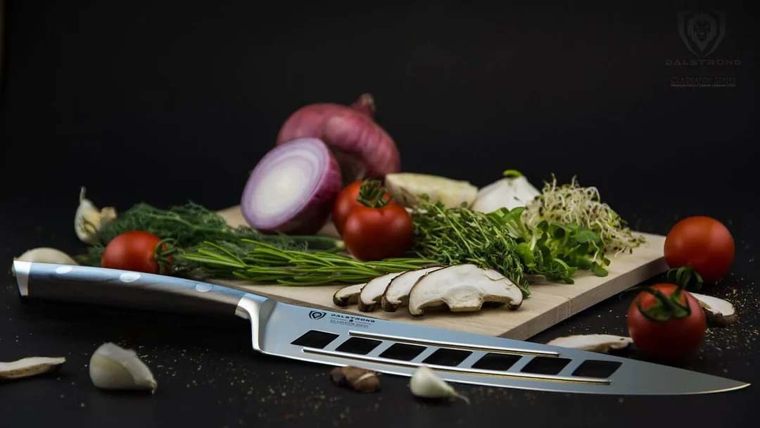 Dalstrong gladiator series 8 inch vegetable knife with black handle surrounded by vegetables and herbs on a cutting board.