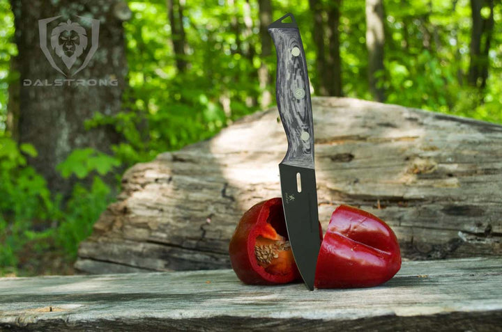 Dalstrong delta wolf series 4 inch paring knife with black blade and a bell pepper cut in half.