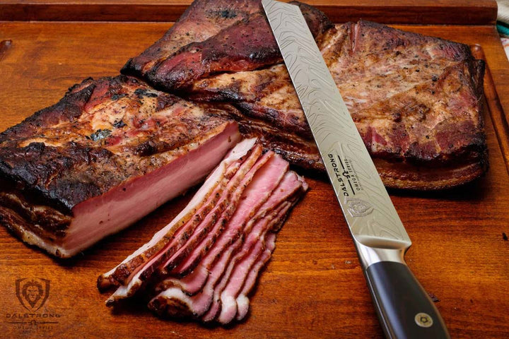 Dalstrong omega series 12 inch slicer knife with slices of cooked pork belly.