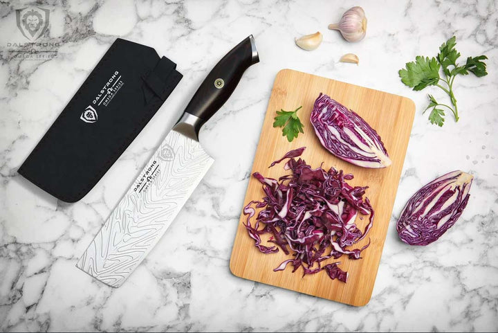 Dalstrong omega series 7 inch nakiri knife with chopped violet cabbage on a cutting board.