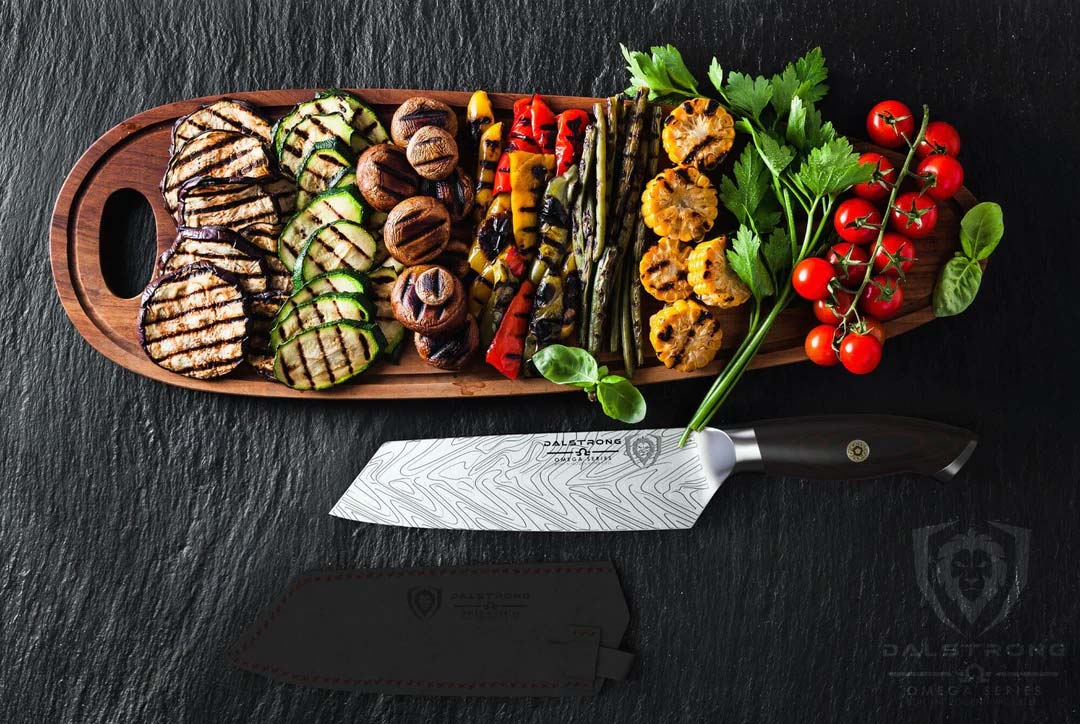 Dalstrong omega series 7 inch santoku knife with grilled vegetables on a wooden board.