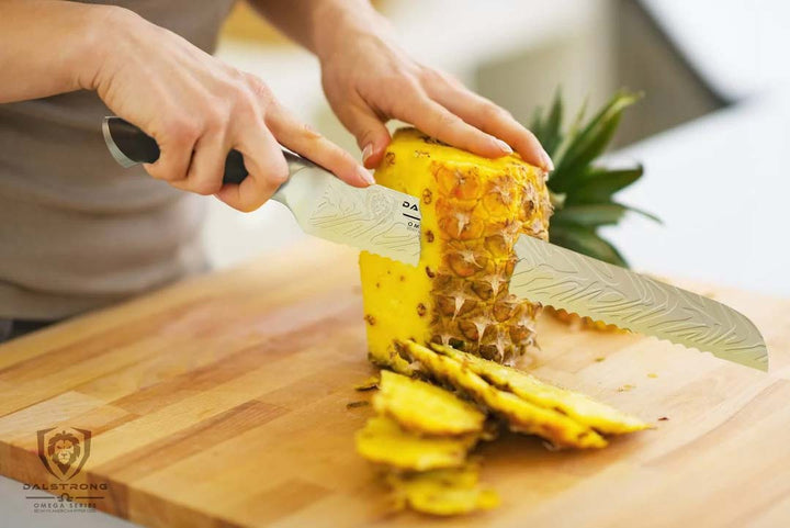 Dalstrong omega series 9 inch bread knife with a sliced pineapple on a cutting board.