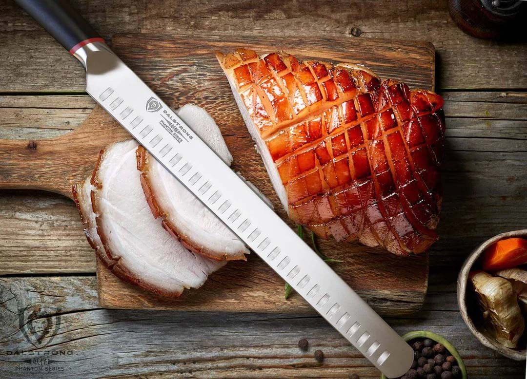 Dalstrong phantom series 12 inch slicer knife with pakka wood handle and slices of ham on a cutting board.