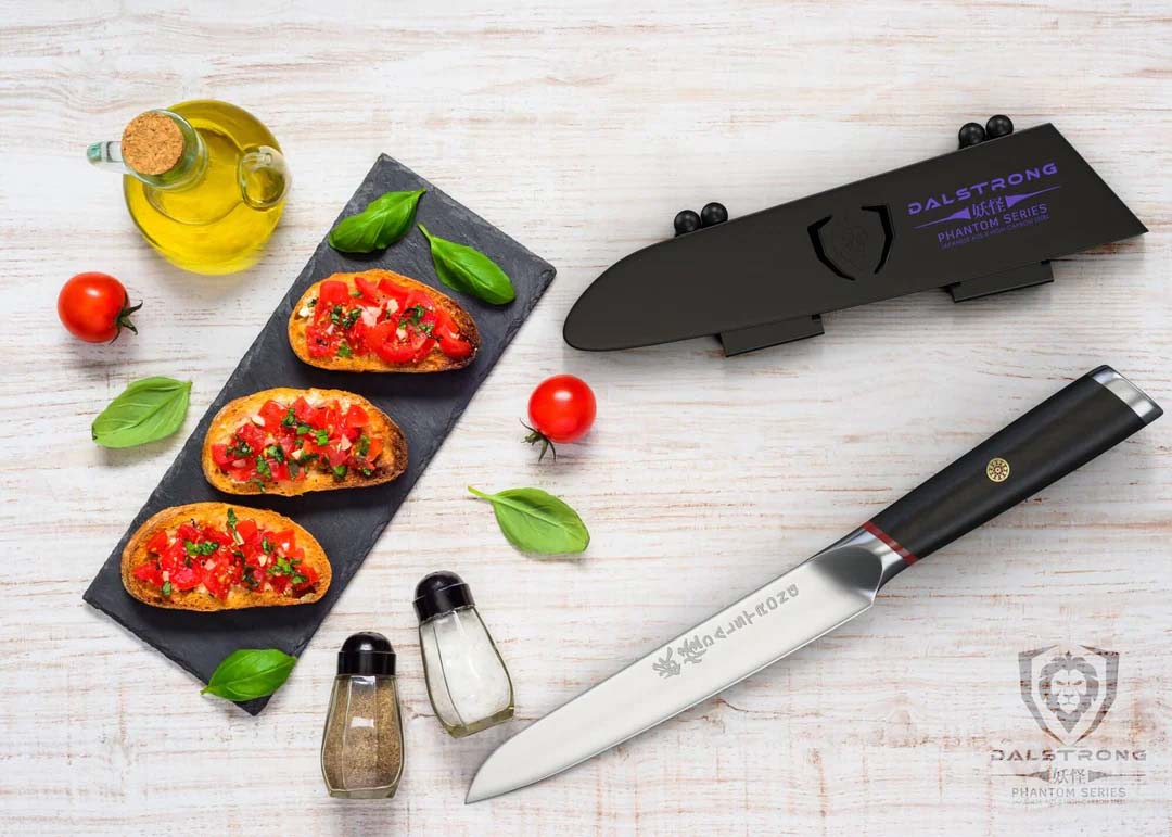 Dalstrong phantom series 5 inch utility knife with pakka wood handle and black sheath beside three tomato sandwiches.
