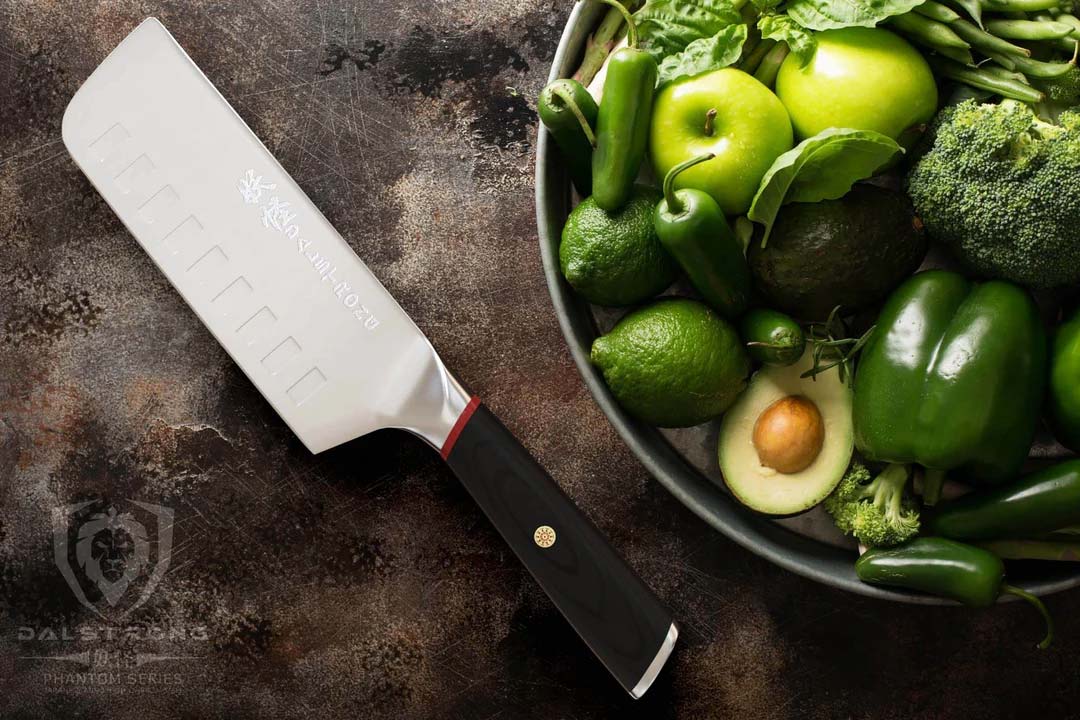 Dalstrong phantom series 6 inch nakiri knife with pakka wood handle beside some vegetables and fruits.