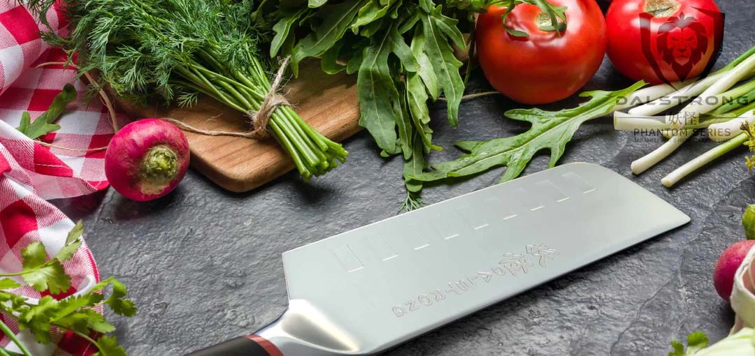 Dalstrong phantom series 6 inch nakiri knife with pakka wood handle surrounded by vegetables and herbs.