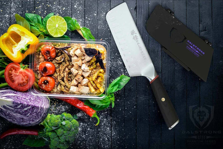 Dalstrong phantom series 6 inch nakiri knife with pakka wood handle and black sheath beside some vegetables.