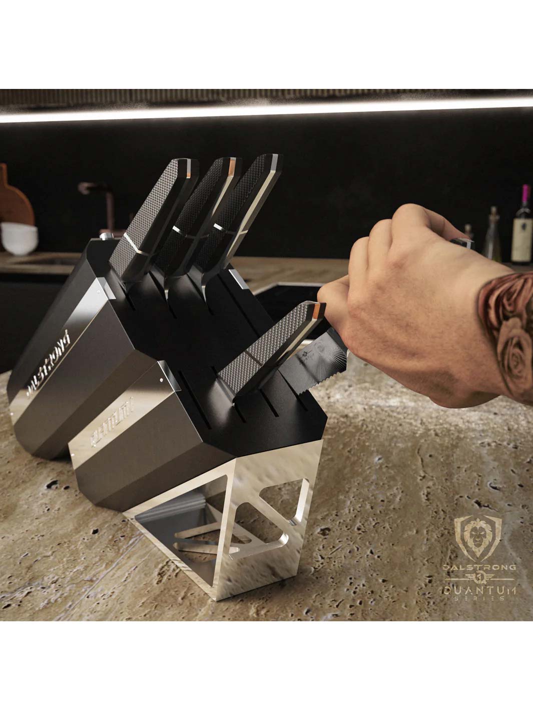 A man's hand holding a knife from the Dalstrong quantum 1 series 5 piece knife block set.