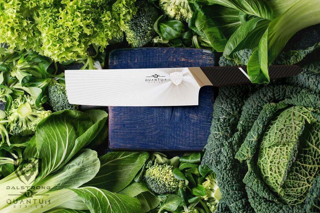 Dalstrong quantum 1 series 7 inch nakiri knife with dragon skin handle surrounded by green vegetables.