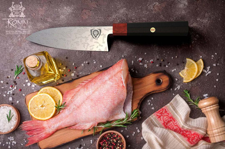 Dalstrong ronin series 6 inch deba knife with black handle and a sliced fish on a cutting board.