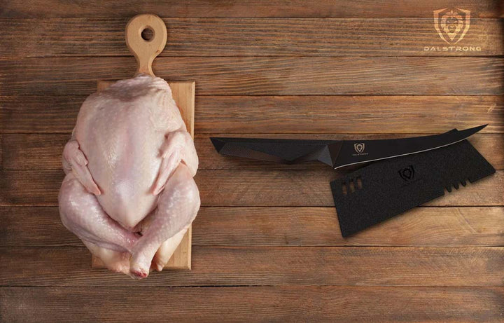 Dalstrong shadow black series 6 inch curved boning knife with black sheath and a whole chicken on a cutting board.