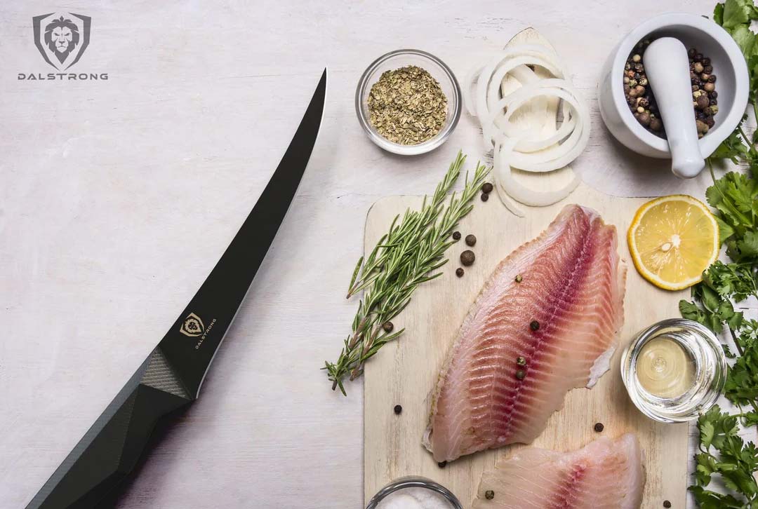 Dalstrong shadow black series 6 inch curved boning knife with black sheath and two fillets of fish on a cutting board.