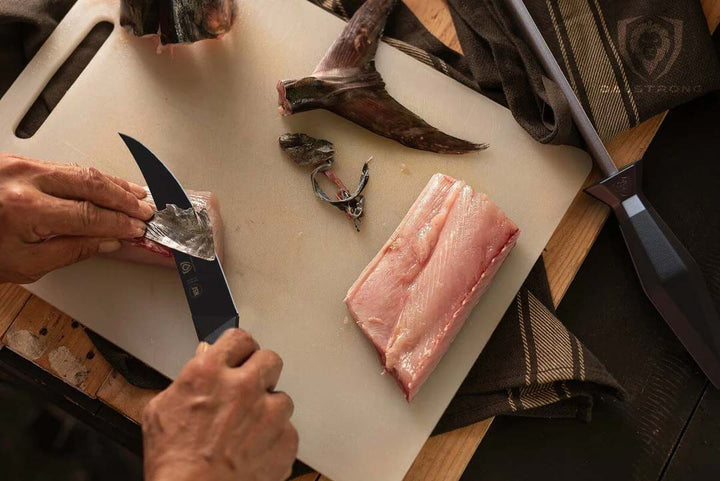 Dalstrong shadow black series 6 inch fillet knife filleting a fish on a cutting board.