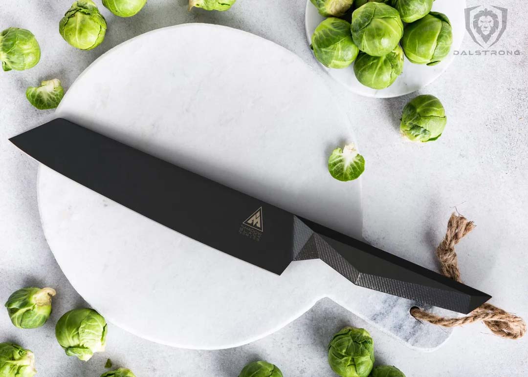 Dalstrong shadow black series 8.5 inch kiiritsuke knife with brussel sprouts on a white cutting board.